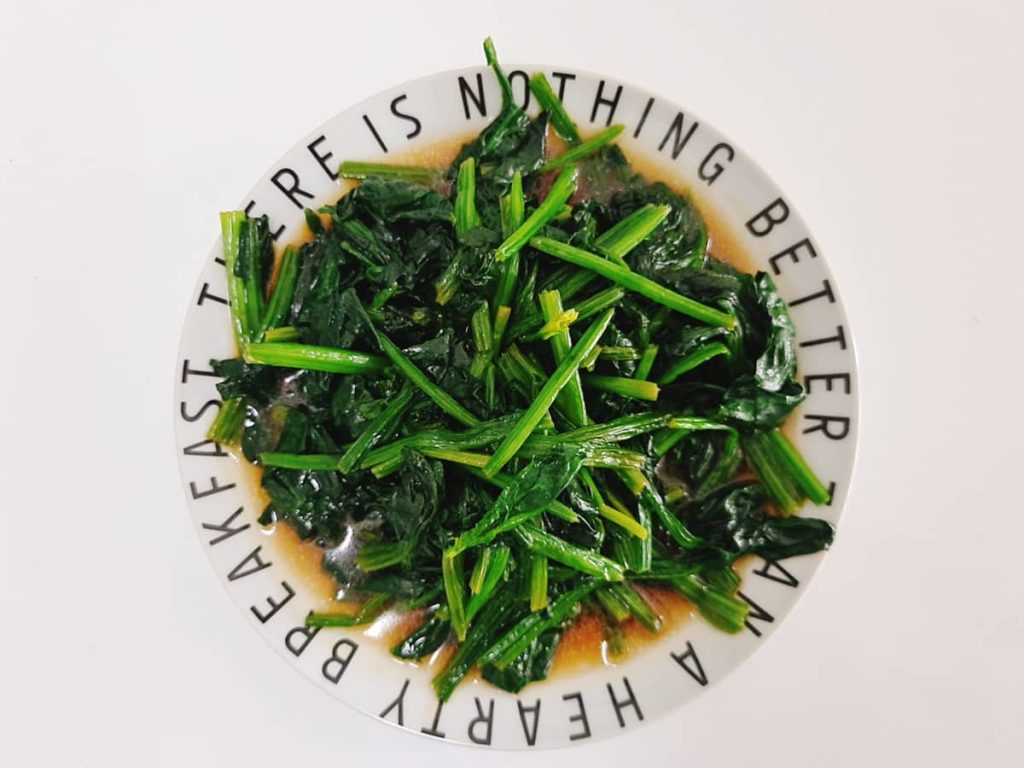 Junyi presenting spinach dish in cultural food showcase