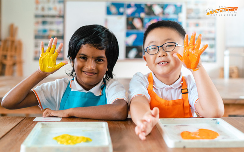 Two children showing off their painted hands at an international school.