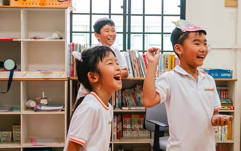 Happy primary school students laughing together in class.