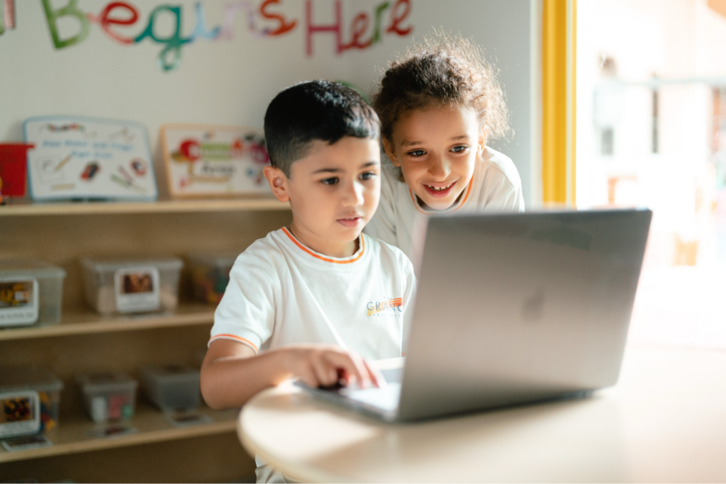 Two young students collaborating on a laptop computer.